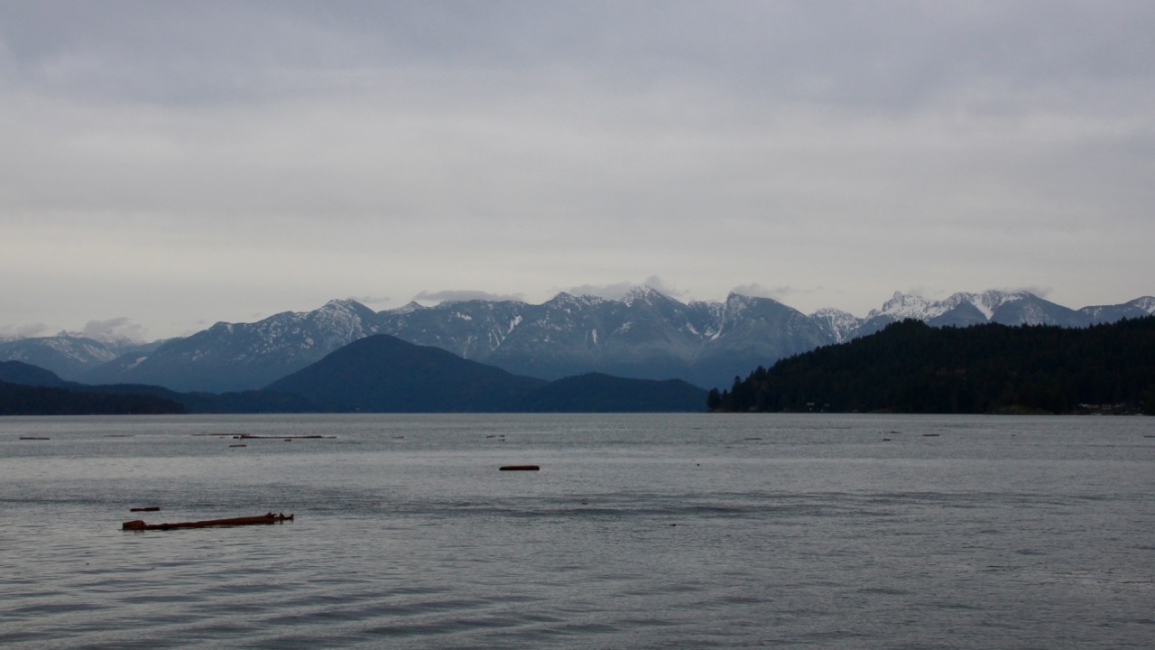 Panorma de plusieurs rangées de montagnes se succédant à l'horizon derrière l'océan.